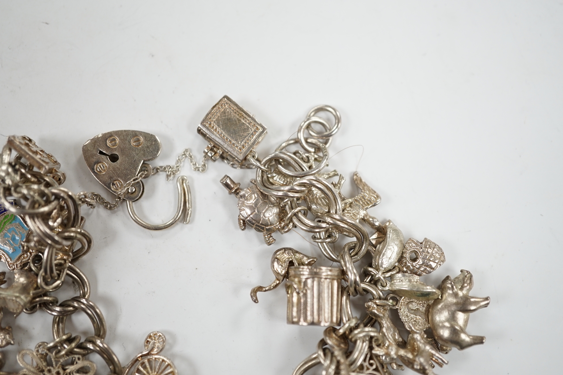 A 1970's silver charm bracelet, hung with assorted charms including birdcage, abacus, piglet, etc. and another silver charm bracelet with loose charms.